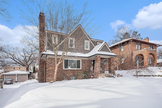 view of front facade featuring an outbuilding, brick siding, a detached garage, and a chimney