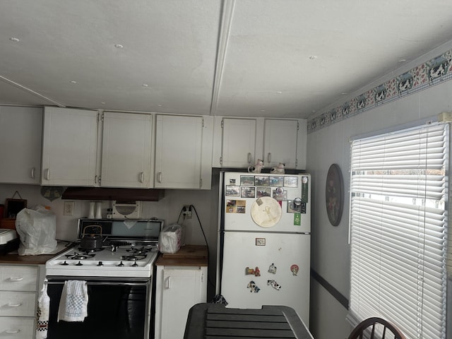 kitchen with white appliances, dark countertops, white cabinetry, and under cabinet range hood