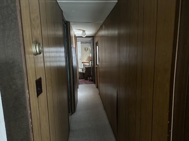 hallway with light carpet and wooden walls