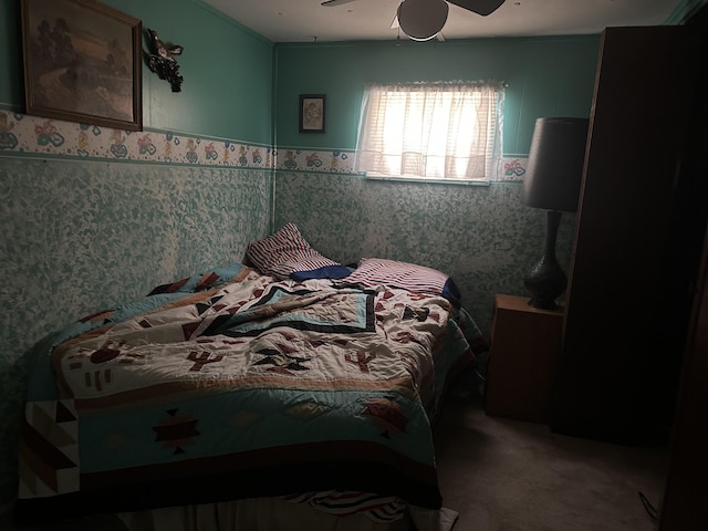 bedroom with carpet floors, a ceiling fan, a wainscoted wall, and wallpapered walls