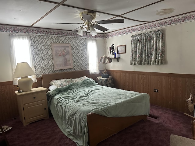 bedroom featuring wainscoting, dark carpet, and ceiling fan