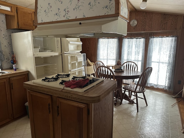 kitchen with wallpapered walls, plenty of natural light, brown cabinetry, and light floors