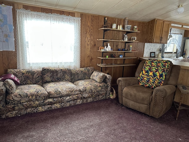 living room with a healthy amount of sunlight, wooden walls, and dark carpet