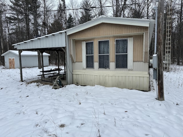 view of snowy exterior with an outbuilding and a storage shed