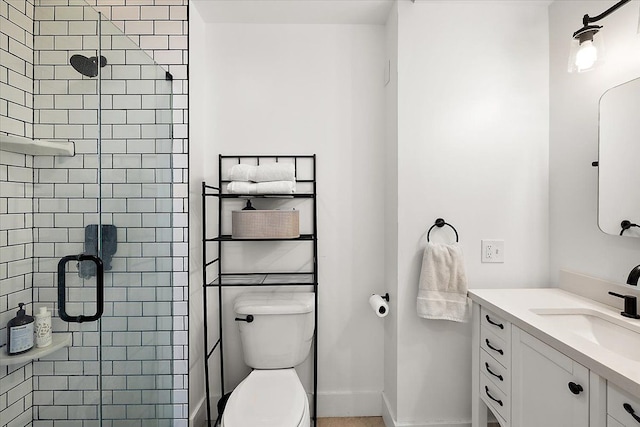 bathroom featuring a stall shower, baseboards, vanity, and toilet