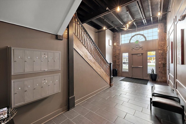 entryway with beam ceiling, stairway, a towering ceiling, mail area, and baseboards