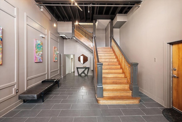 stairway featuring a towering ceiling, baseboards, and tile patterned floors