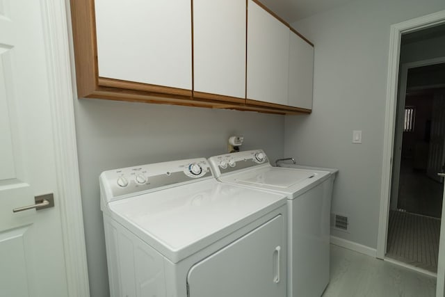 washroom with cabinet space, visible vents, washer and dryer, and baseboards