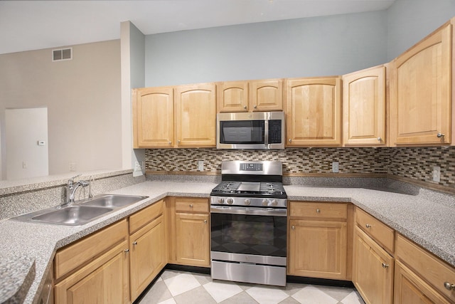 kitchen featuring visible vents, appliances with stainless steel finishes, a sink, and light brown cabinetry