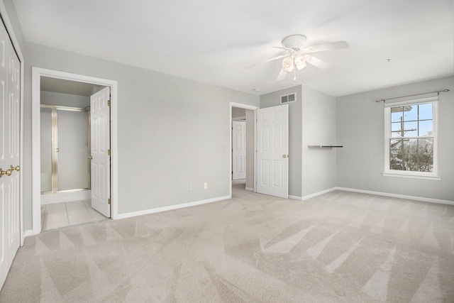 unfurnished bedroom featuring light colored carpet, visible vents, connected bathroom, ceiling fan, and baseboards