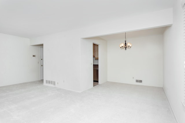 unfurnished room with visible vents, carpet flooring, and an inviting chandelier