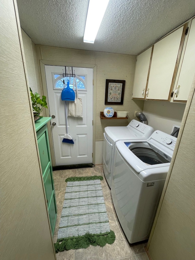 laundry room featuring a textured ceiling, washer and clothes dryer, and cabinet space