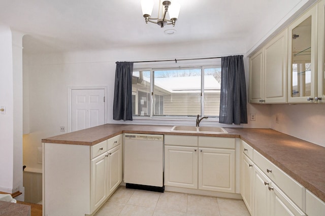 kitchen featuring glass insert cabinets, light tile patterned flooring, a sink, a chandelier, and dishwasher