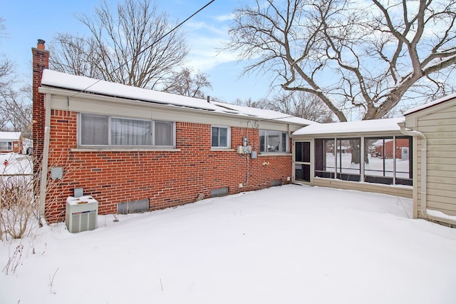 view of front of property featuring brick siding, a chimney, and cooling unit