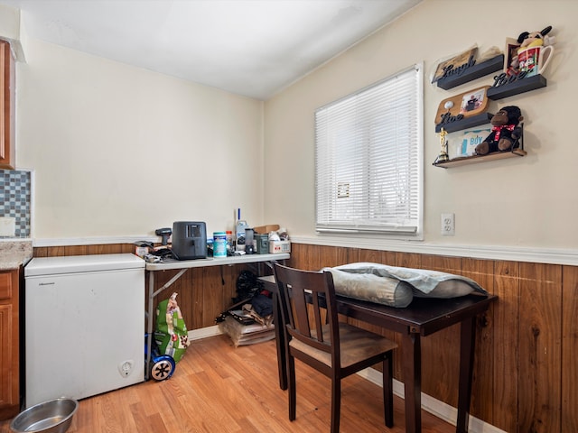 office area featuring wainscoting, wooden walls, and light wood finished floors