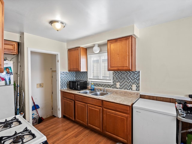 kitchen with tasteful backsplash, brown cabinets, light countertops, black microwave, and a sink