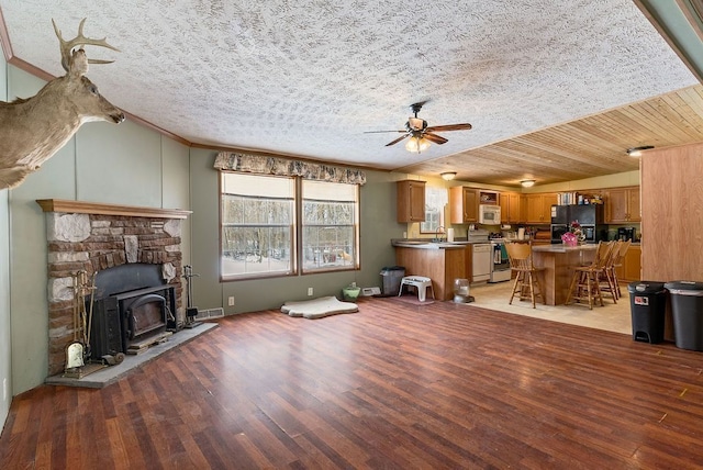 living room with crown molding, a ceiling fan, visible vents, and light wood-style floors