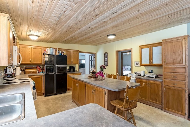 kitchen featuring a breakfast bar area, white appliances, a sink, a kitchen island, and brown cabinetry