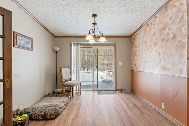 unfurnished room featuring a textured ceiling, ornamental molding, and wood finished floors