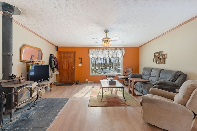 living room with a wood stove, crown molding, a textured ceiling, and wood finished floors