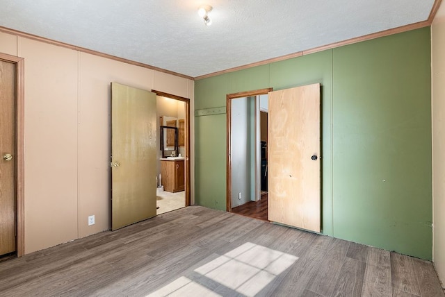 unfurnished bedroom with a textured ceiling, ornamental molding, and wood finished floors