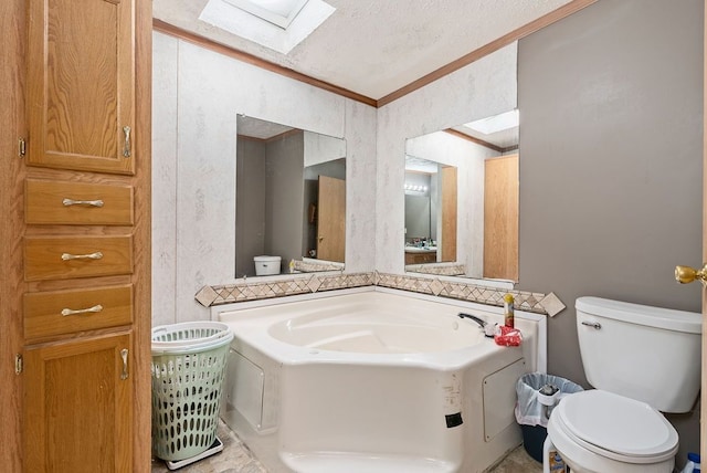 full bath featuring a textured ceiling, a garden tub, toilet, a skylight, and crown molding