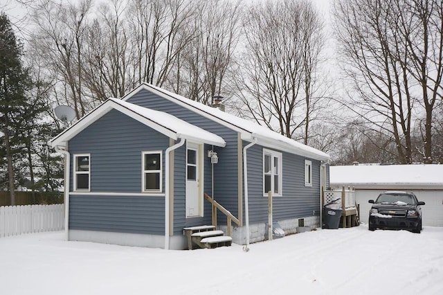 view of front of property with entry steps, a detached garage, a chimney, and fence