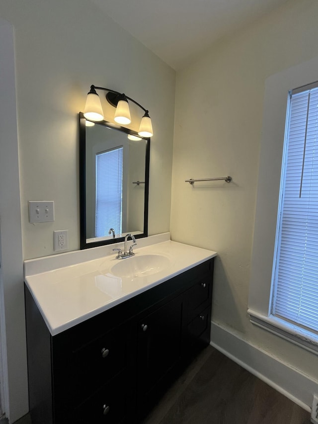 bathroom with visible vents, vanity, baseboards, and wood finished floors