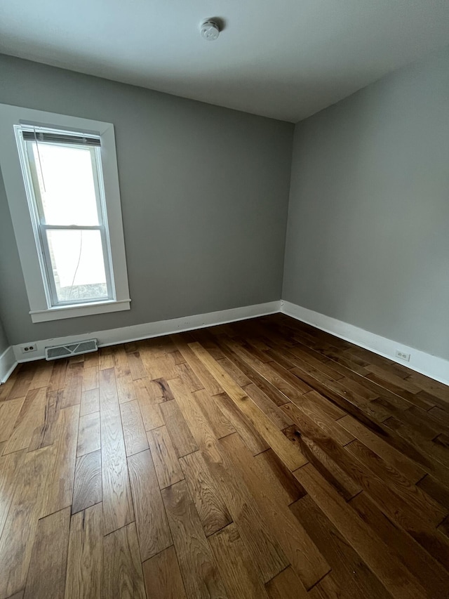 spare room with light wood finished floors, visible vents, and baseboards