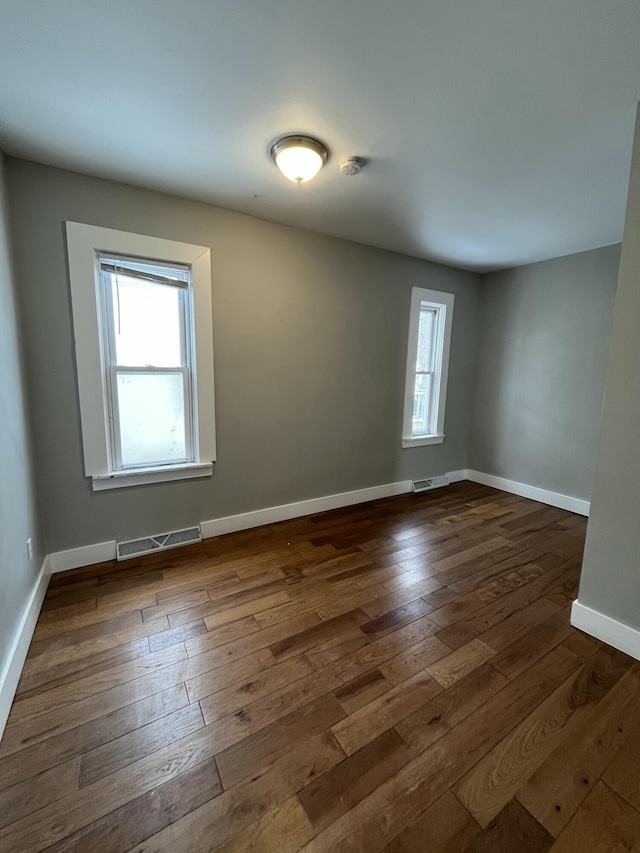 spare room featuring dark wood-style floors, baseboards, and visible vents