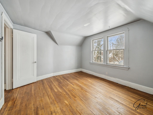 bonus room featuring vaulted ceiling, light wood-style flooring, and baseboards