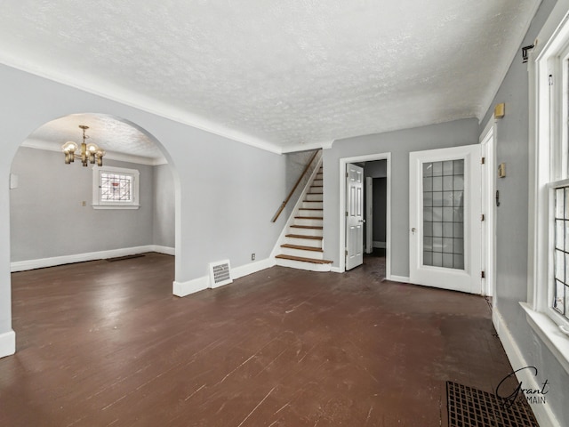 unfurnished living room with arched walkways, visible vents, stairway, and a textured ceiling