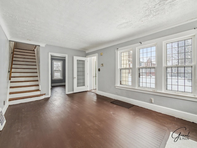 entrance foyer featuring a textured ceiling, dark wood-type flooring, visible vents, baseboards, and stairs