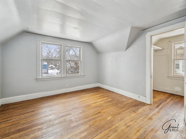 bonus room with lofted ceiling, light wood finished floors, and baseboards