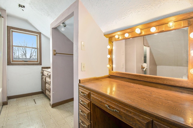 bathroom featuring baseboards, lofted ceiling, tile patterned floors, a textured ceiling, and vanity