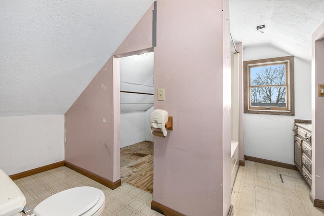 bathroom with lofted ceiling, baseboards, a textured ceiling, and tile patterned floors