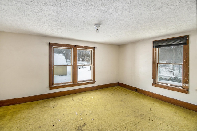 unfurnished room featuring a textured ceiling and baseboards