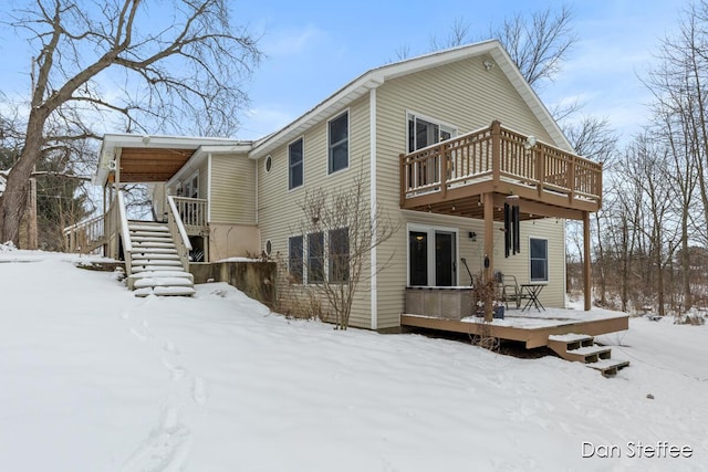 snow covered house featuring stairs and a wooden deck