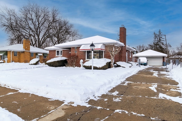 view of front of house featuring an outbuilding, brick siding, a chimney, and a detached garage