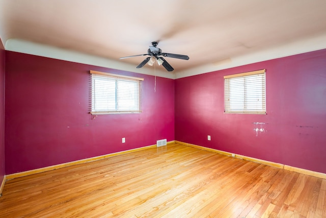 spare room with a ceiling fan, baseboards, visible vents, and wood finished floors