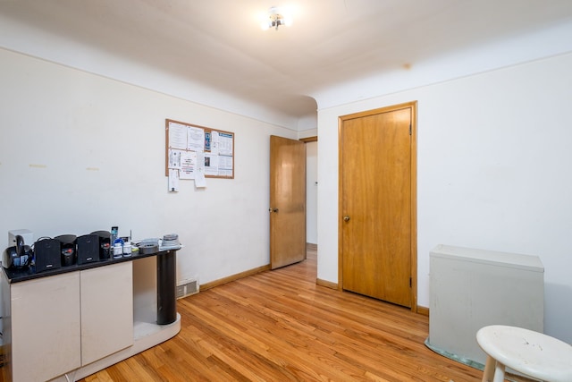 home office with light wood-type flooring, visible vents, and baseboards