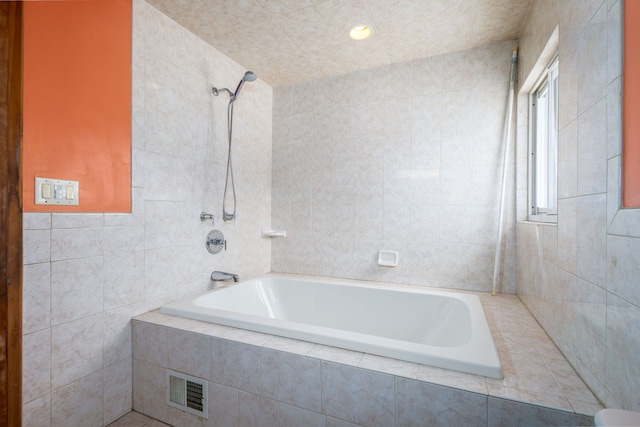 bathroom featuring visible vents, tiled shower / bath combo, and tile walls