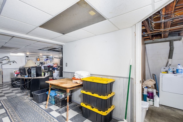 finished basement with concrete block wall, washer / dryer, dark floors, and a wainscoted wall