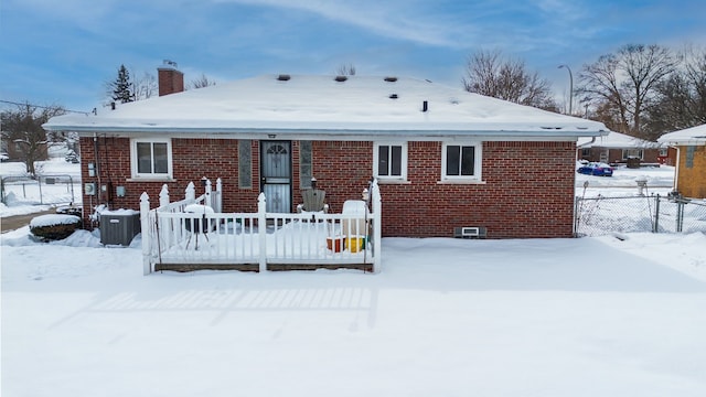 snow covered property featuring brick siding and a chimney