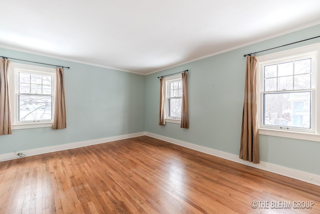 unfurnished room featuring baseboards, crown molding, light wood-type flooring, and a healthy amount of sunlight