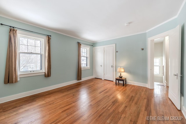 empty room with light wood-style floors, baseboards, and crown molding