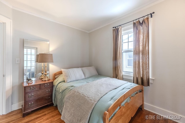 bedroom featuring ornamental molding, multiple windows, light wood-type flooring, and baseboards