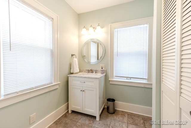 bathroom with a closet, vanity, and baseboards