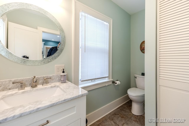 bathroom featuring a closet, toilet, vanity, baseboards, and tile patterned floors