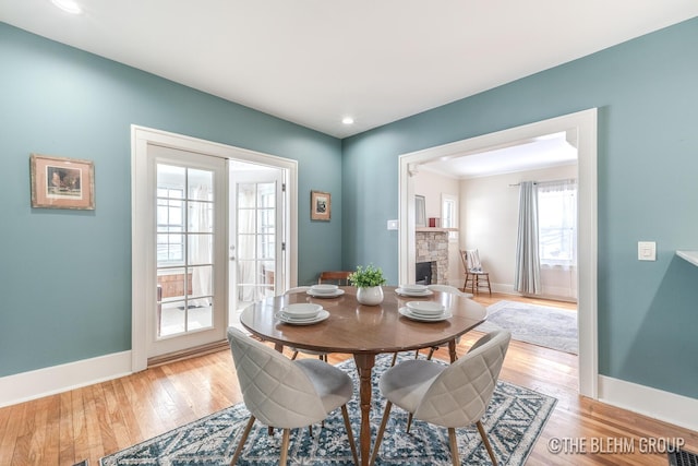 dining room with baseboards, a fireplace, and light wood-style floors